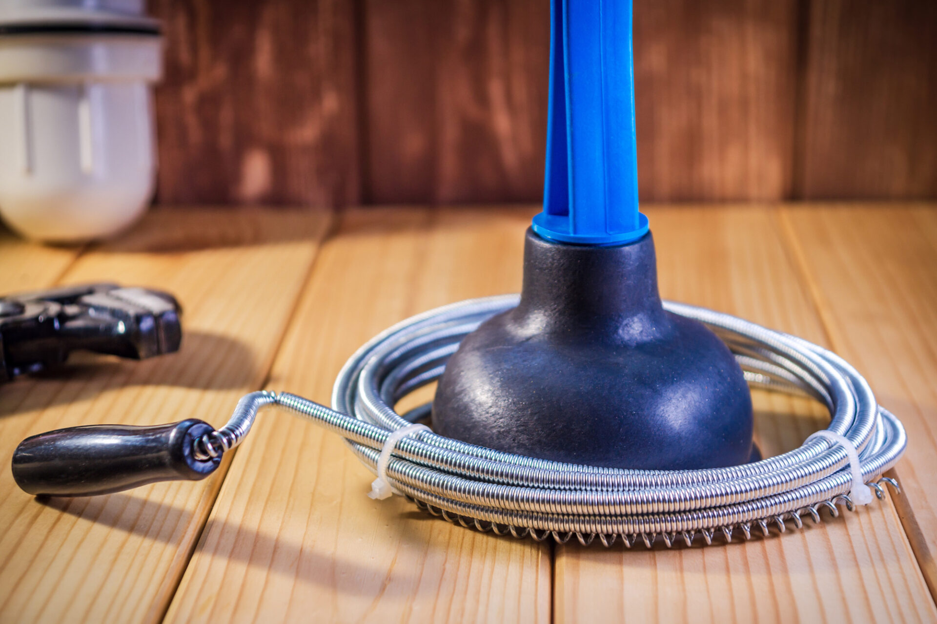 Clean plastic plunger with blue handle and cable on wooden background