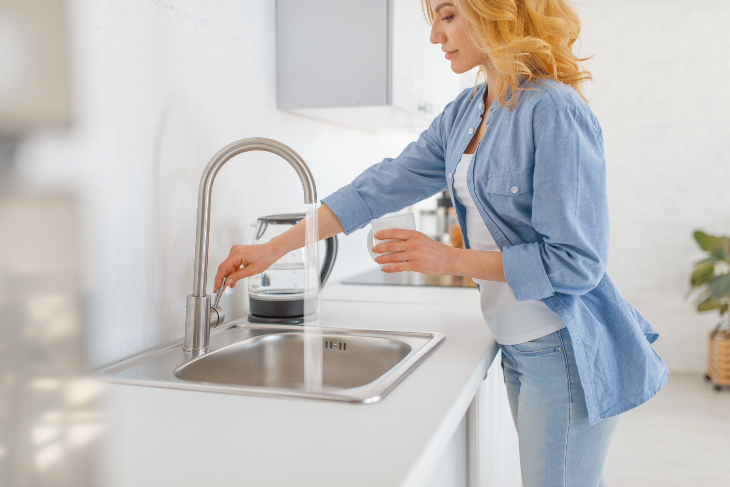 Young woman with glass at the sink on the kitchen